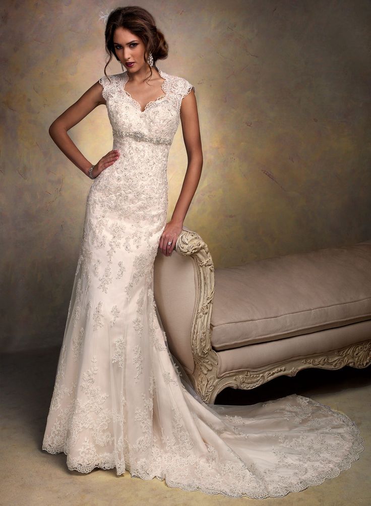 a woman in a white wedding dress standing next to a couch with her hands on her hips