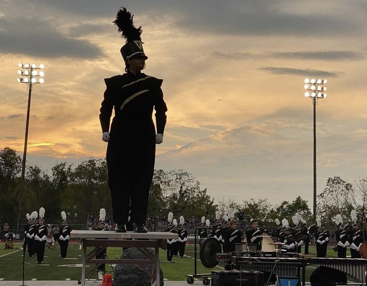 a marching band is performing in front of an audience at the stadium as the sun sets