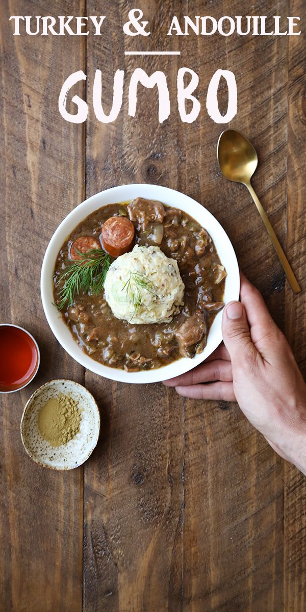 a person holding a spoon over a bowl of food on a wooden table with the words turkey and andoulie gumbo