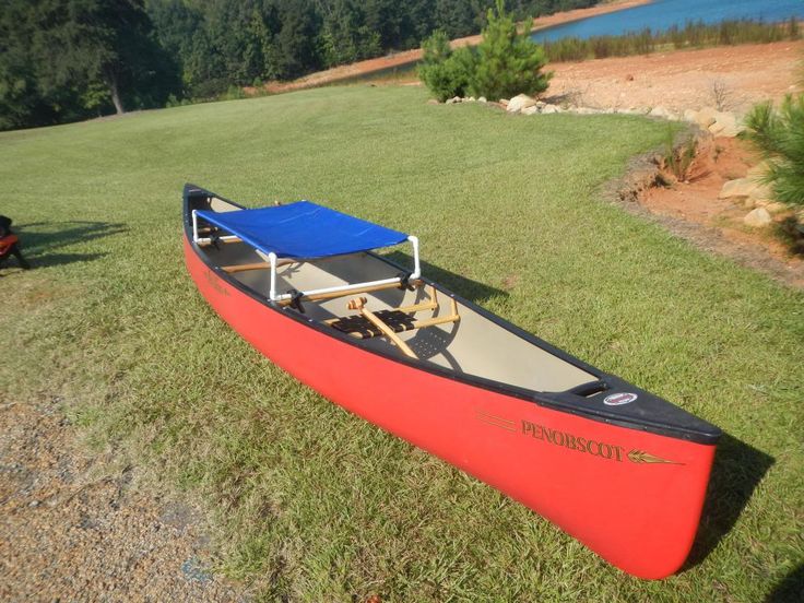 a red canoe sitting on top of a lush green field