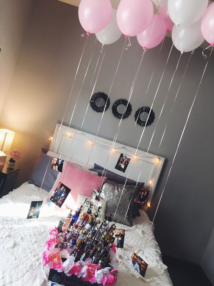 balloons are hanging from the ceiling above a bed with pictures and pink flowers on it