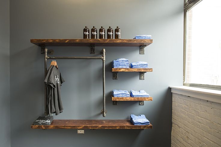 two shelves with towels and bottles on them next to a window in a room that has blue walls