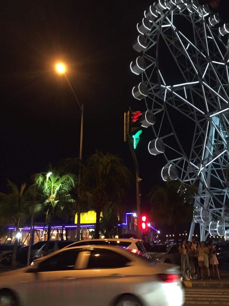 a large ferris wheel sitting on the side of a road next to a traffic light