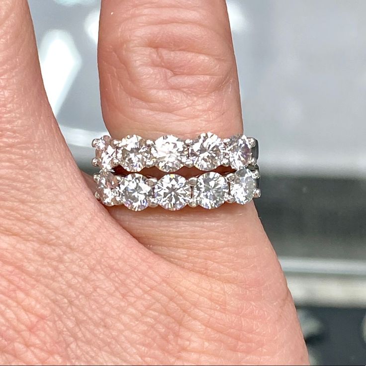 a woman's hand with a diamond ring on it, and the band is in between her fingers