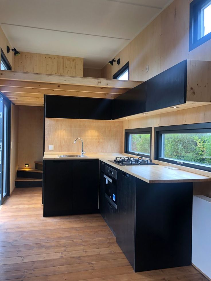 an empty kitchen with wood floors and black cabinets