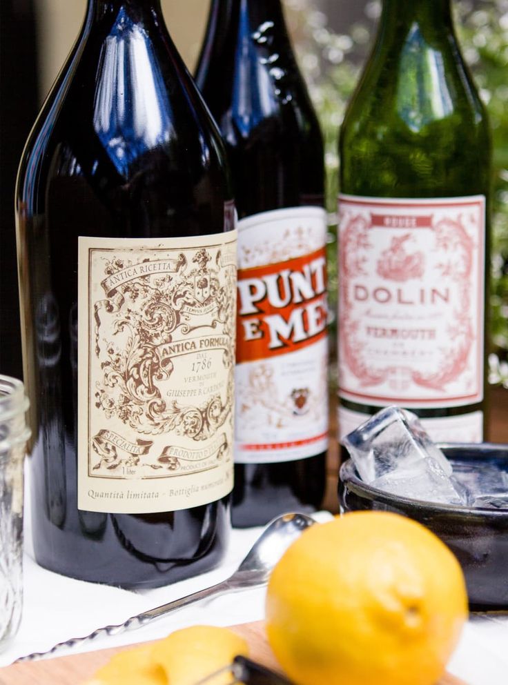 three bottles of wine sitting on top of a table next to two lemons and a knife