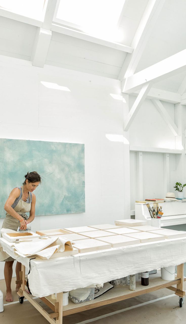 a woman is working on an art piece in a room with white walls and ceilings