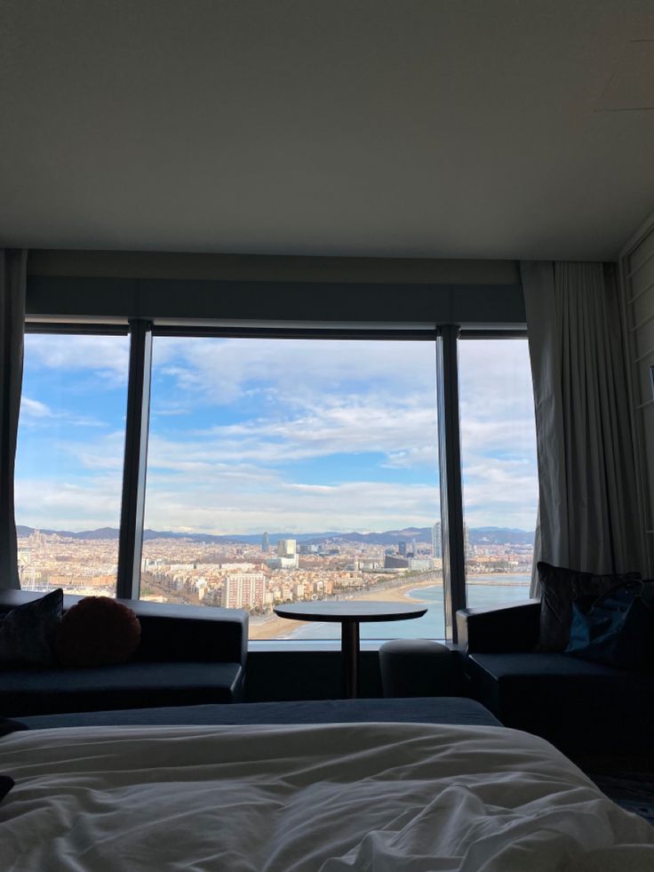 a bed sitting next to a large window in a living room under a blue sky