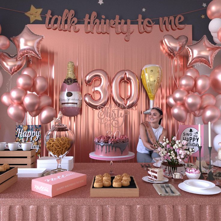 a woman sitting at a table in front of balloons, cake and other desserts