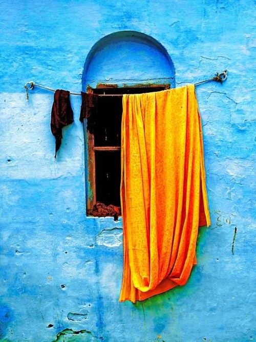 an orange cloth hanging out to dry on a blue wall