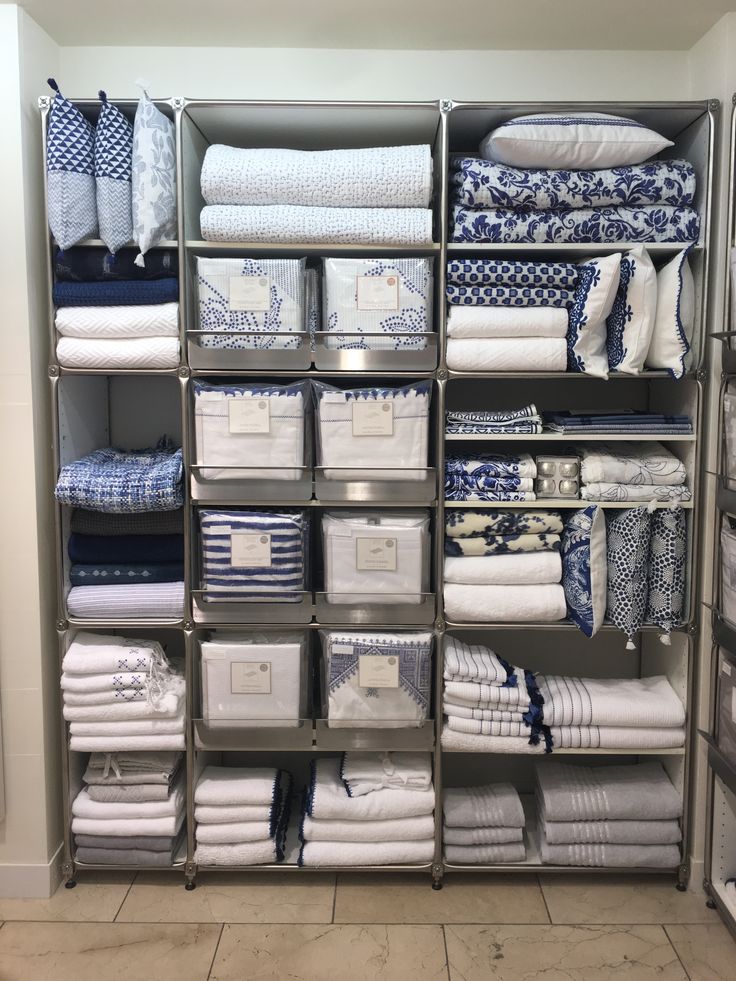 an organized closet filled with folded towels and folded linens in blue and white colors