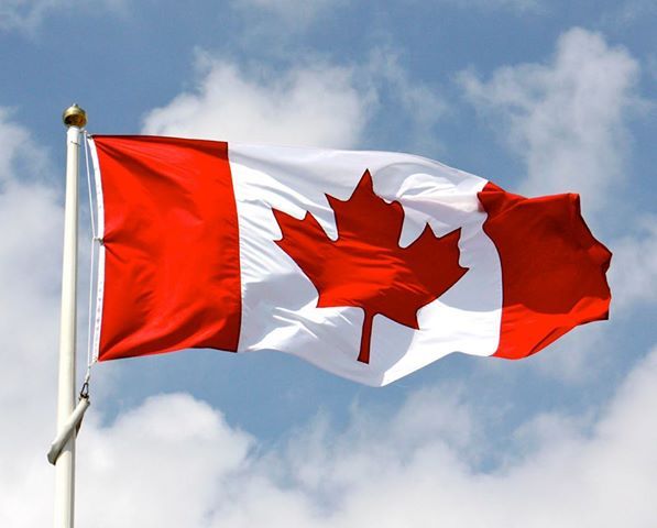 the canadian flag is flying high in the sky