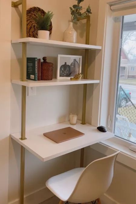 a white desk with some books on it and a chair in front of the window