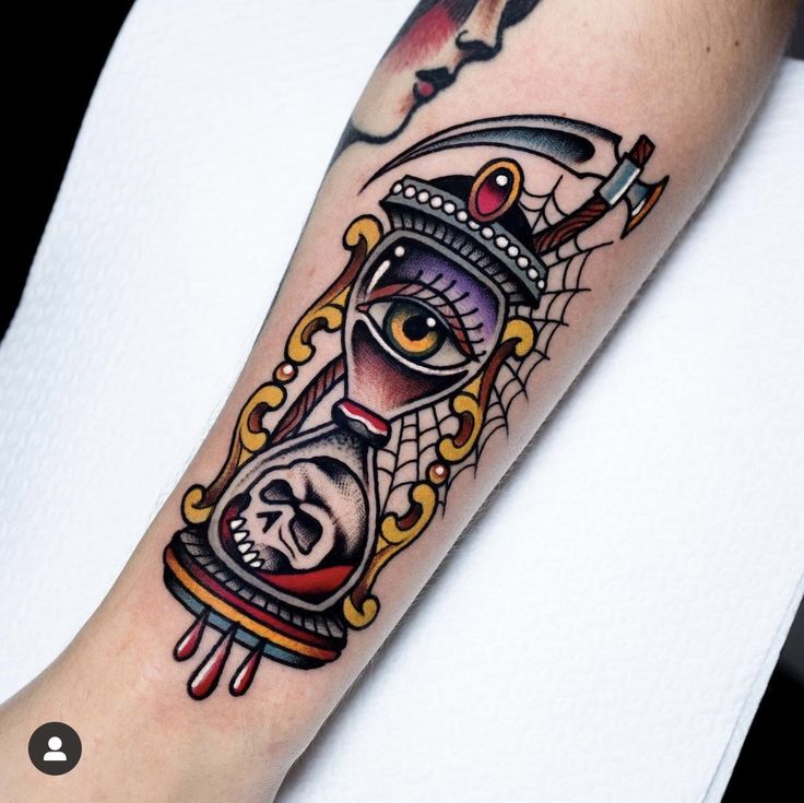 a tattoo on the arm of a person with an eye and hourglass in it