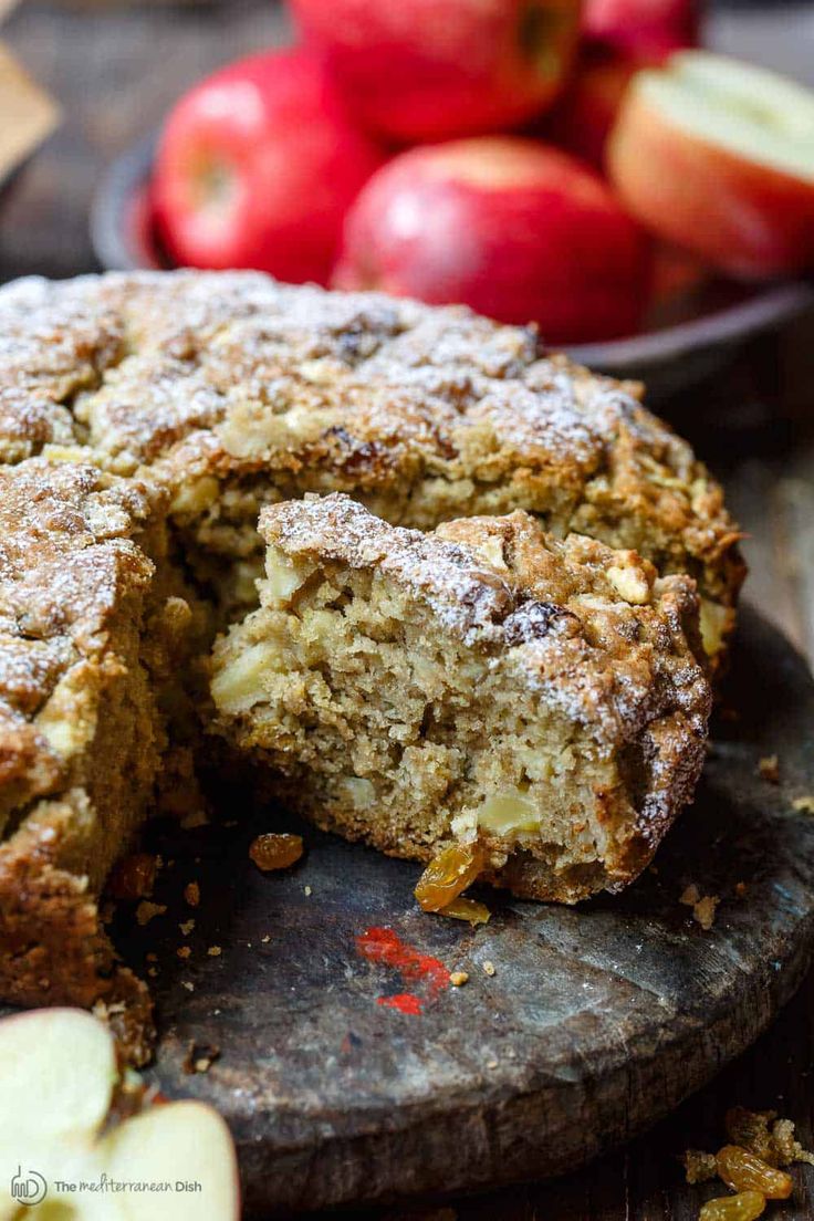 an apple cake is cut in half on a cutting board with some apples behind it