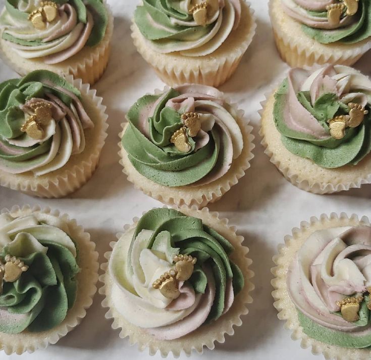 cupcakes decorated with green and pink frosting on a white tableclothed surface