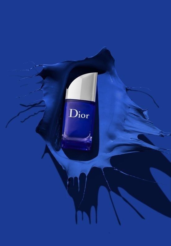 a bottle of dior perfume sitting on top of a blue liquid splashing surface