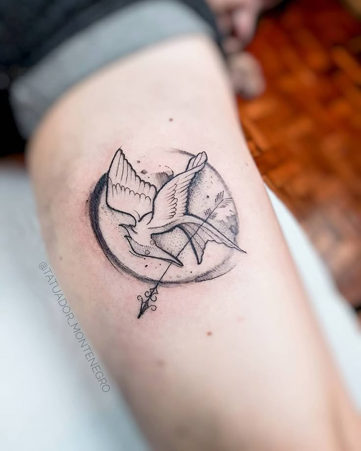 a tattoo on the leg of a person with a bird flying over it's head