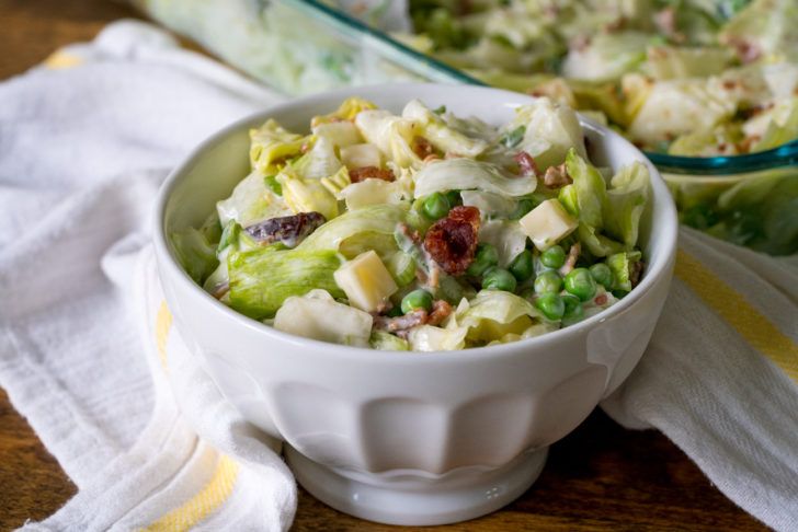 a white bowl filled with salad on top of a wooden table next to a glass dish