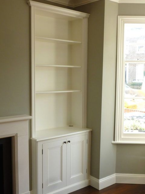 an empty room with a fireplace and built in bookshelves next to a window