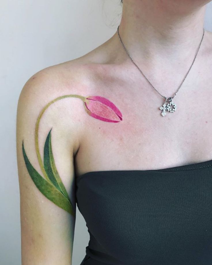 a woman with a flower tattoo on her shoulder and chest, showing the outline of a pink tulip