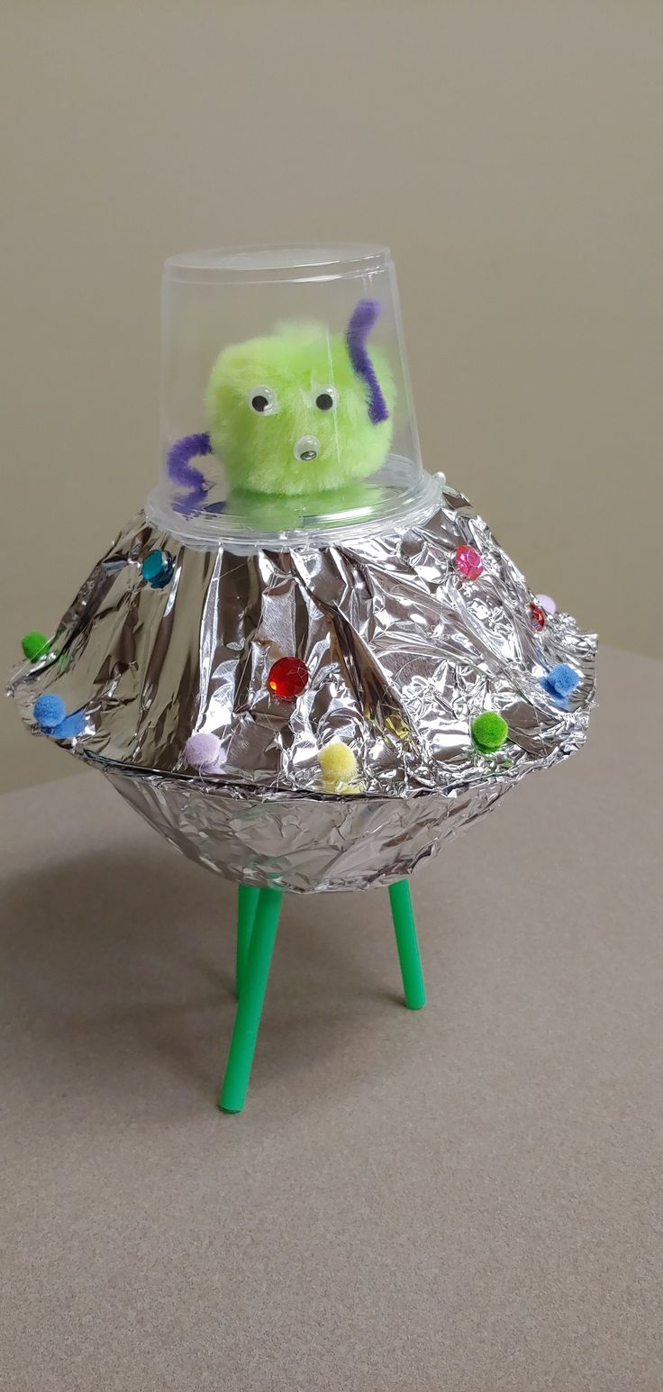 a green object sitting on top of a piece of tin foil covered in magnets