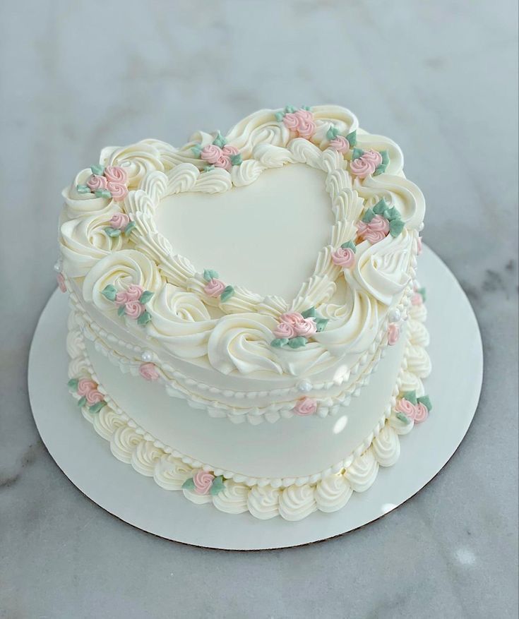 a heart shaped cake on a white plate with pink and green flowers in the shape of a heart