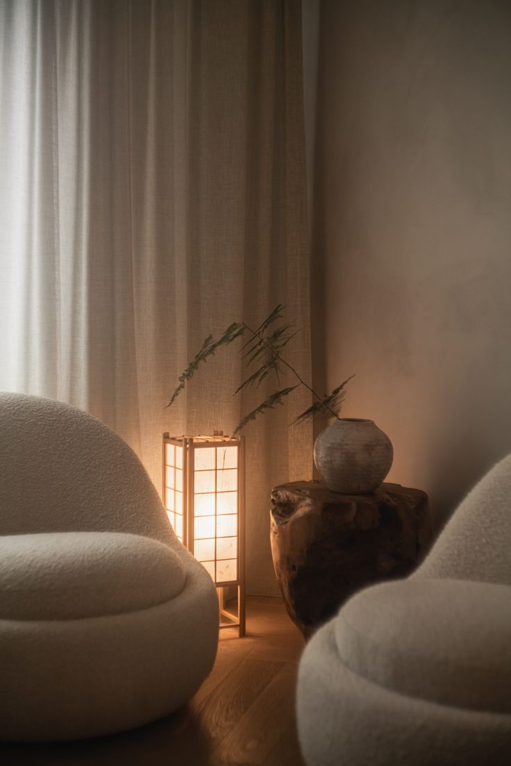 a white chair sitting next to a table with a vase on it's side