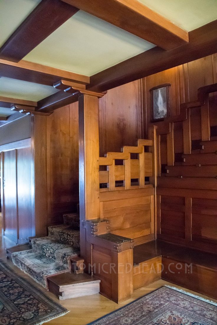 a room with wood paneling and stairs leading to the second floor, along with an area rug on the floor