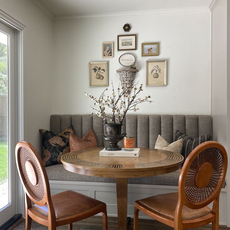 a table and chairs in a room with pictures on the wall above it, along with a bench