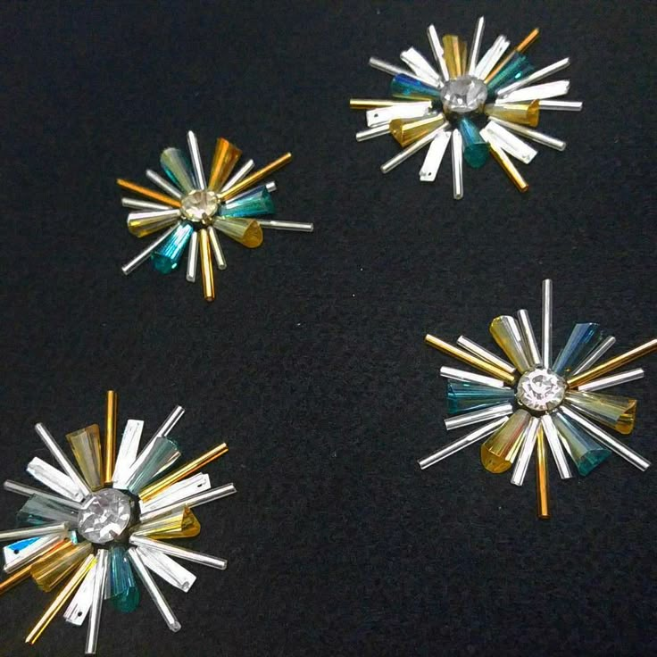 four different types of brooches on a black surface with gold, silver and blue pins