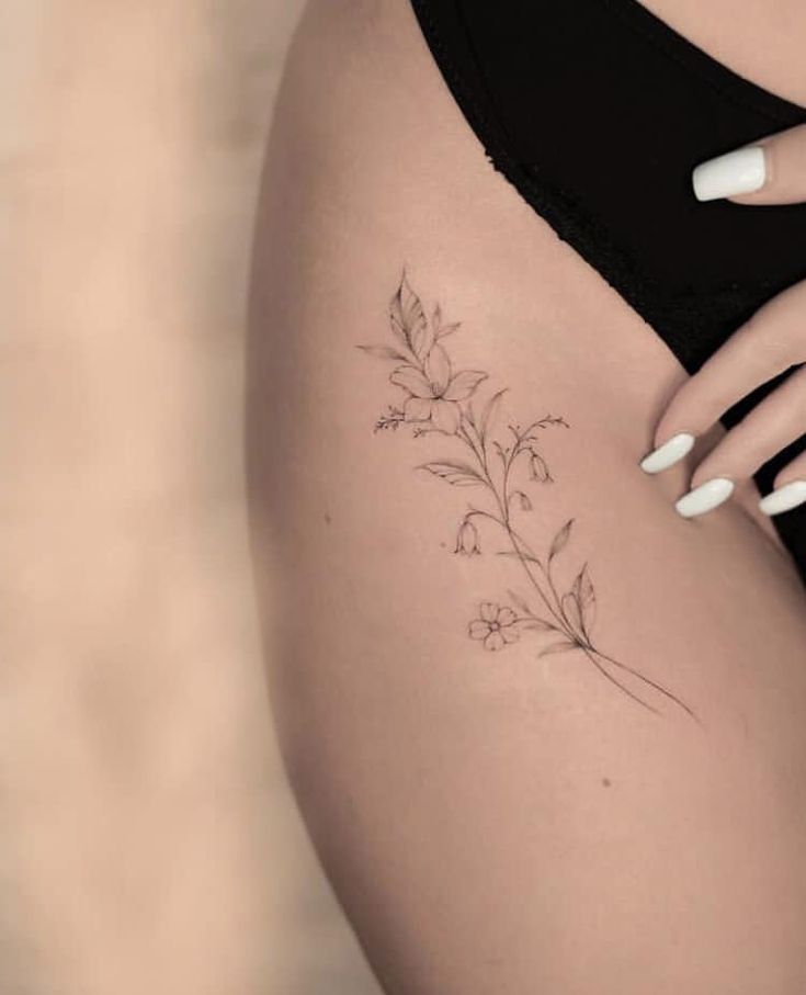 a close up of a woman's stomach with tattoos on it and flowers in the side