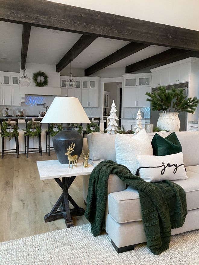 a living room filled with white furniture and christmas decorations on top of wooden flooring