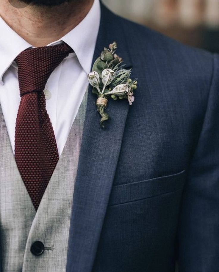 a man wearing a suit and tie with a boutonniere on his lapel