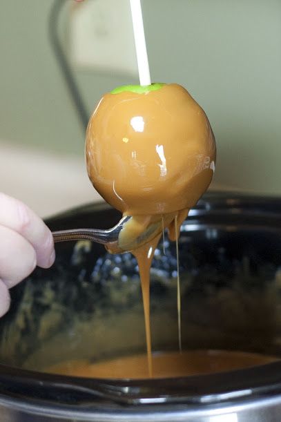 a person is spooning caramel sauce into a crock pot with a ladle