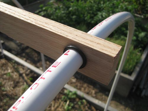 two white pipes are connected to a wooden post