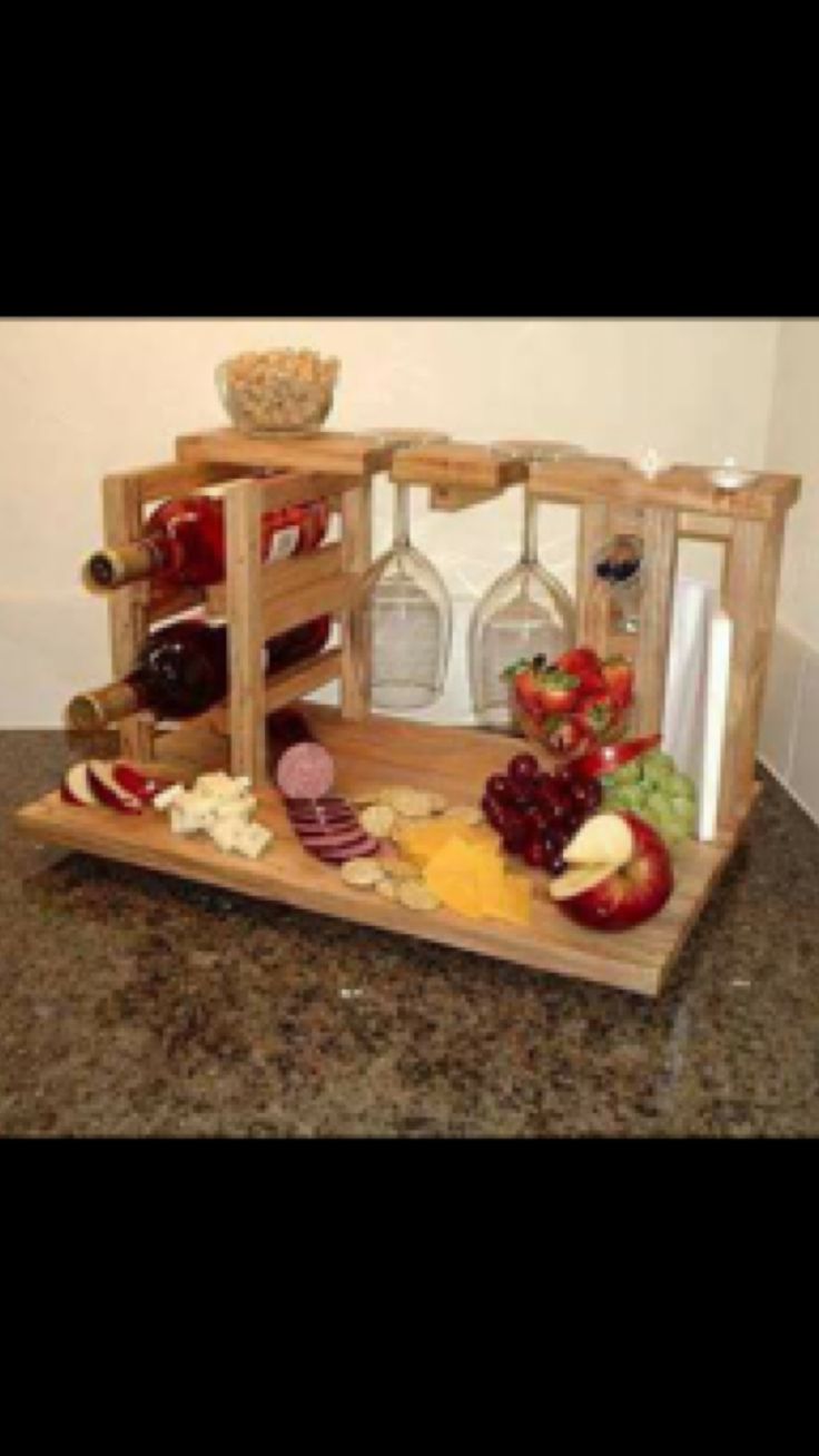 a wooden tray filled with cheese and meats on top of a counter next to a wall