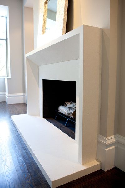 a white fireplace with a mirror on the wall and hardwood floors in front of it