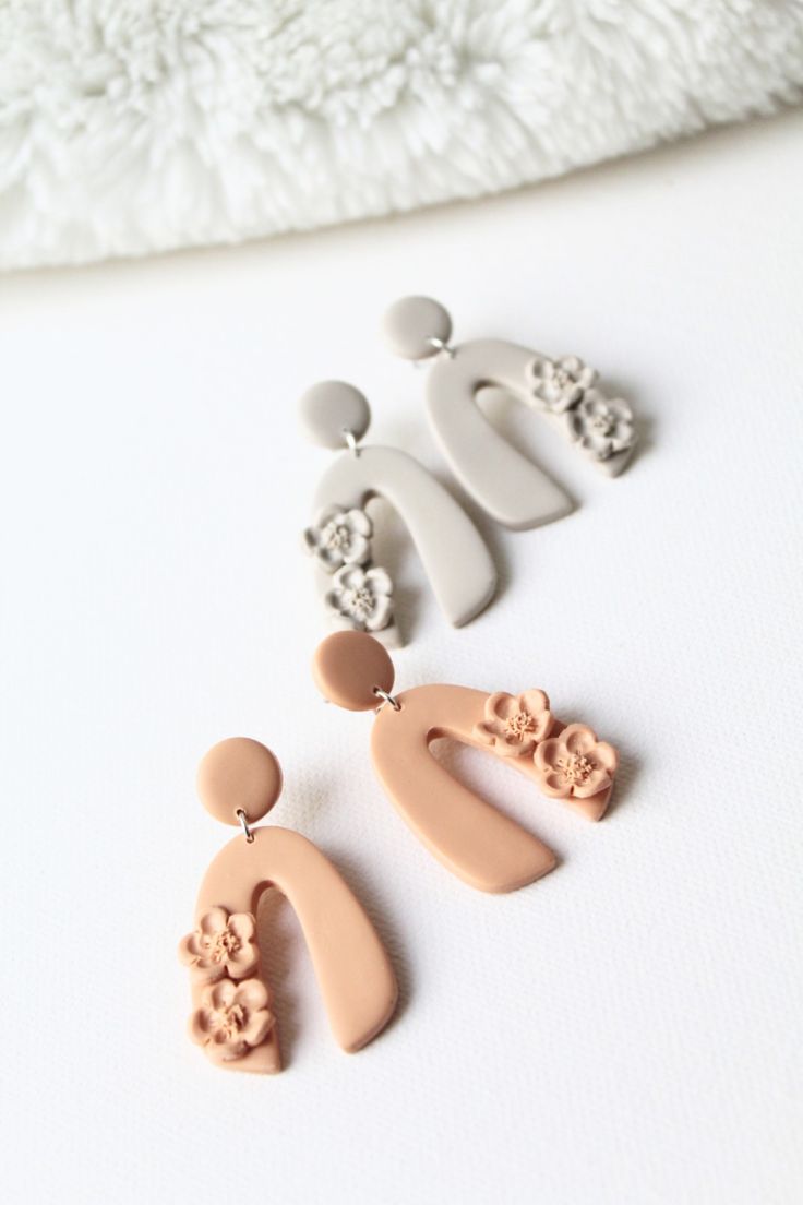 three pairs of earrings on a white surface