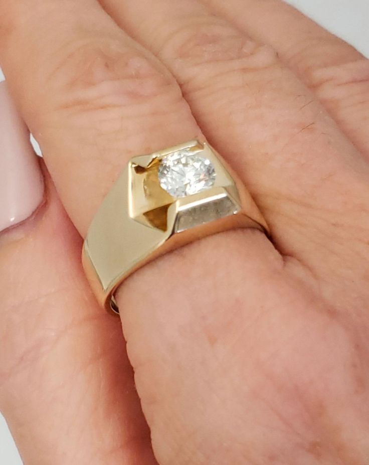 a woman's hand with a gold ring on it and a pink manicure