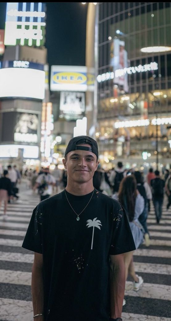 a young man standing in the middle of a crosswalk at night with people walking around