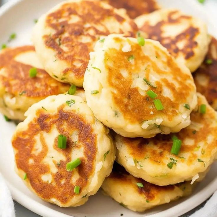 several pancakes on a white plate with green onions and chives in the middle, ready to be eaten