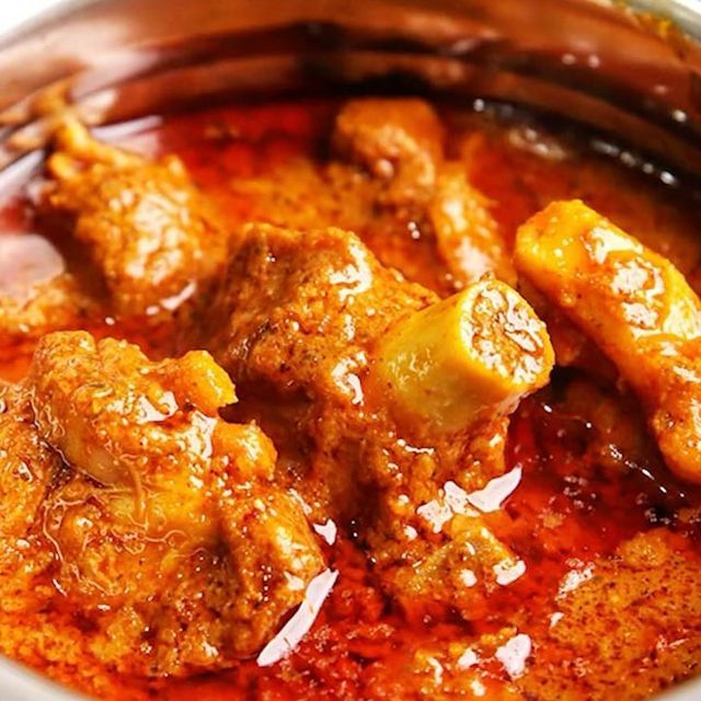 a close up of a bowl of food with meat and vegetables in sauce on the side