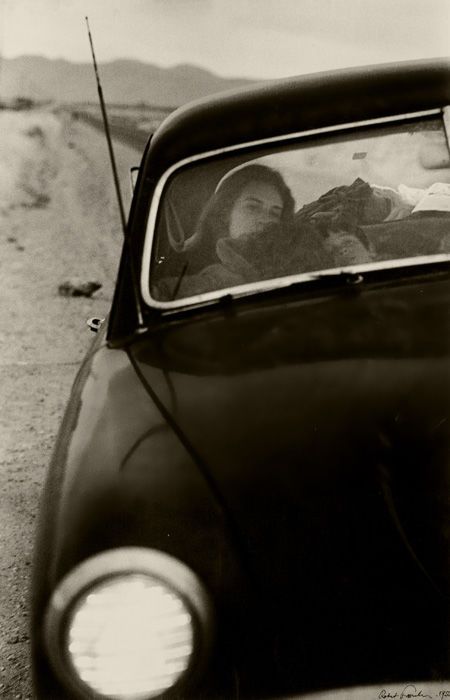 a black and white photo of a woman in a car with her head out the window