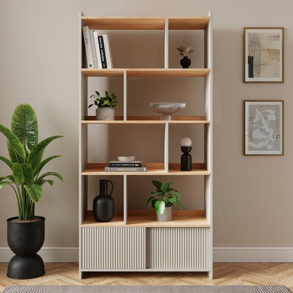 a living room with a potted plant and bookshelf on the floor next to it