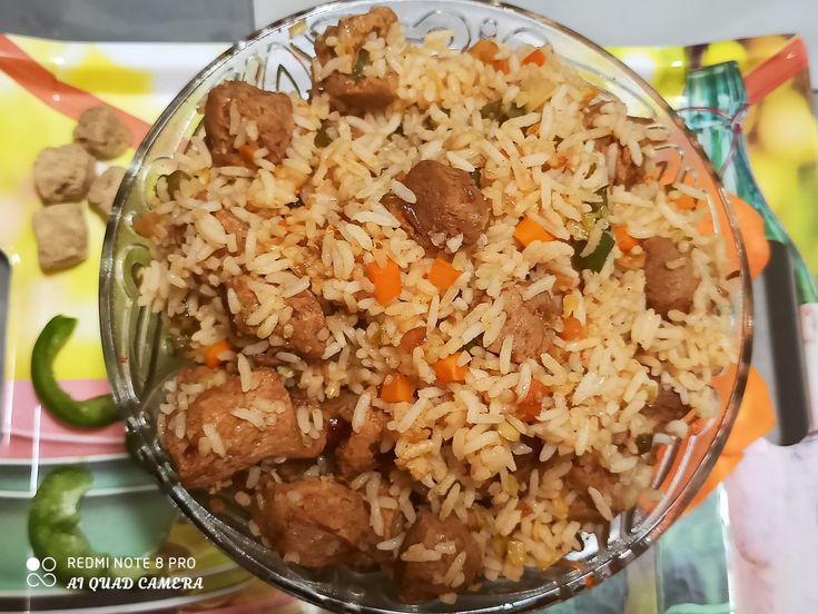 a glass bowl filled with rice and meat