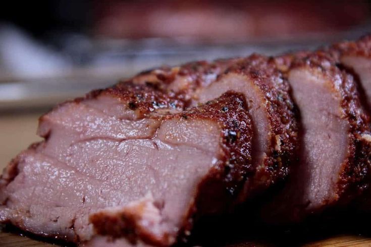 sliced meat sitting on top of a wooden cutting board