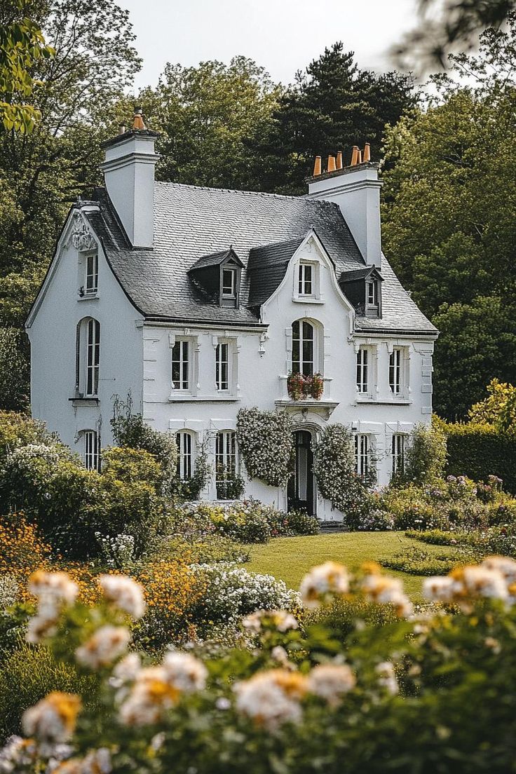 a large white house surrounded by flowers and trees