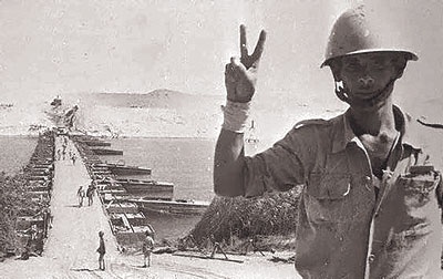 a man in an army uniform is giving the peace sign while standing on a beach