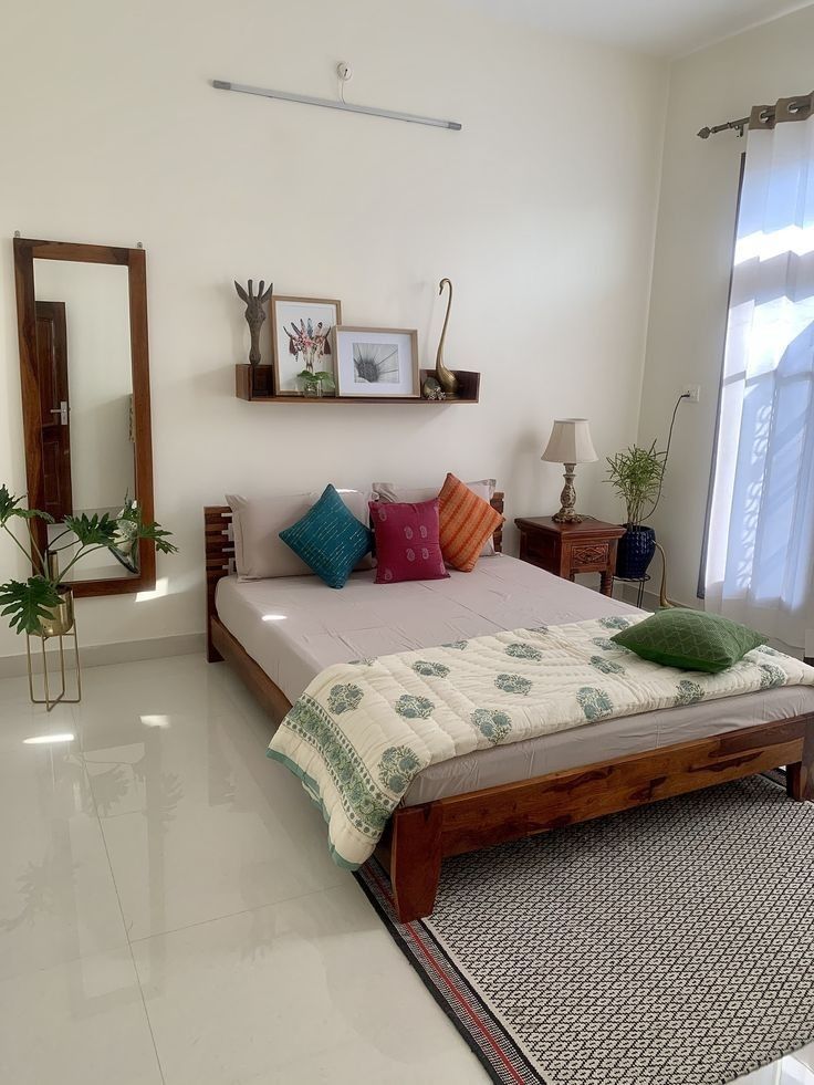 a bed sitting in the middle of a living room next to a mirror and window